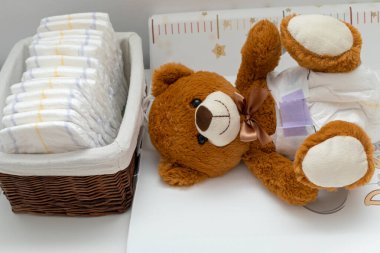 Bebek yatağında bebek bezi takmış kahverengi bir ayı heykeli.