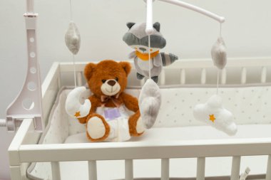 Bebek yatağında bebek bezi takmış kahverengi bir ayı heykeli.
