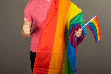 Pembe tişört ve gökkuşağı bayrağı giymiş eşcinsel bir adam.