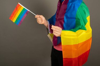 Pembe tişört ve gökkuşağı bayrağı giymiş eşcinsel bir adam.