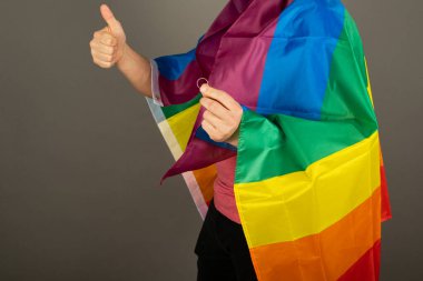 Pembe tişört ve gökkuşağı bayrağı giymiş eşcinsel bir adam.