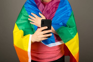 Pembe tişört ve gökkuşağı bayrağı giymiş eşcinsel bir adam.