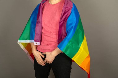 Pembe tişört ve gökkuşağı bayrağı giymiş eşcinsel bir adam.