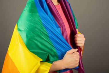 Pembe tişört ve gökkuşağı bayrağı giymiş eşcinsel bir adam.