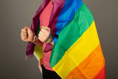 Pembe tişört ve gökkuşağı bayrağı giymiş eşcinsel bir adam.