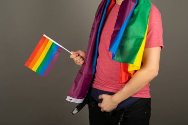 Pembe tişört ve gökkuşağı bayrağı giymiş eşcinsel bir adam.