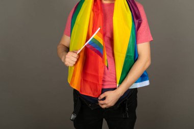 Pembe tişört ve gökkuşağı bayrağı giymiş eşcinsel bir adam.