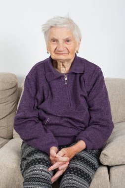 Kanepede oturan yaşlı bir kadının portresi.