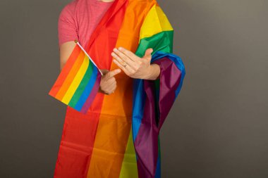 Pembe tişört ve gökkuşağı bayrağı giymiş eşcinsel bir adam.