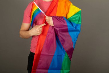 Pembe tişört ve gökkuşağı bayrağı giymiş eşcinsel bir adam.