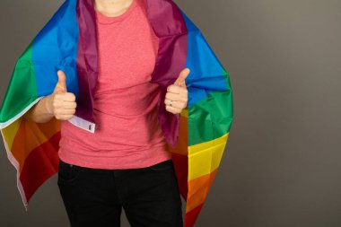 Pembe tişört ve gökkuşağı bayrağı giymiş eşcinsel bir adam.