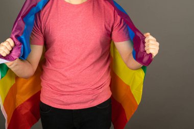 Pembe tişört ve gökkuşağı bayrağı giymiş eşcinsel bir adam.
