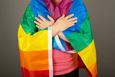 Pembe tişört ve gökkuşağı bayrağı giymiş eşcinsel bir adam.