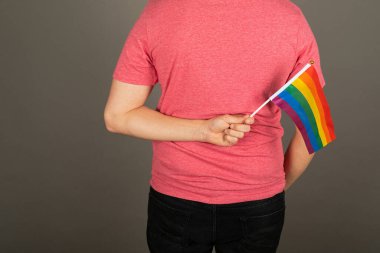 Pembe tişört ve gökkuşağı bayrağı giymiş eşcinsel bir adam.