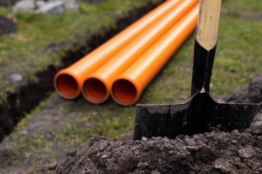 Turuncu PVC drenaj borularını yere seriyor.