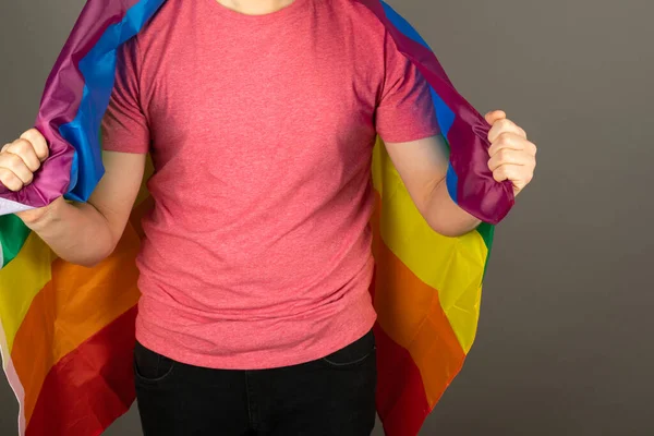 Pembe tişört ve gökkuşağı bayrağı giymiş eşcinsel bir adam.