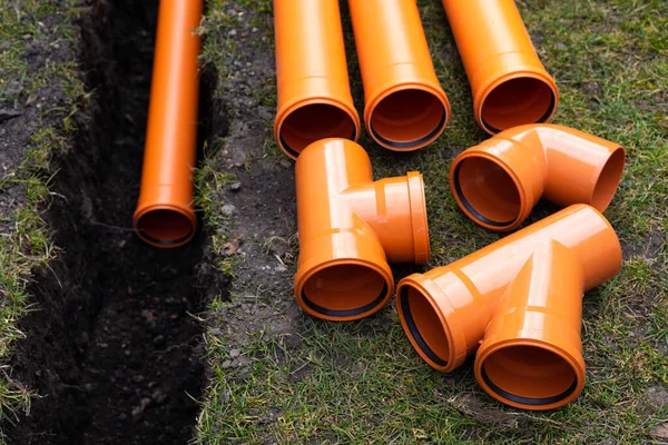 Laying down orange PVC drainage pipes into the ground