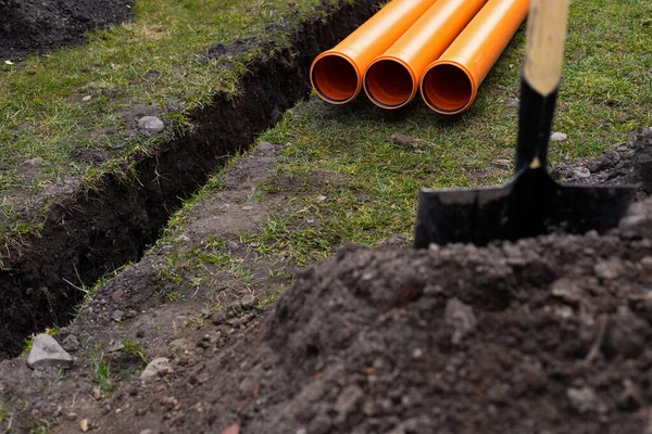 Laying down orange PVC drainage pipes into the ground