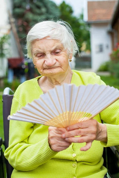 Senior Woman Holding Waving Fan Hot Summer Day Stock Photo