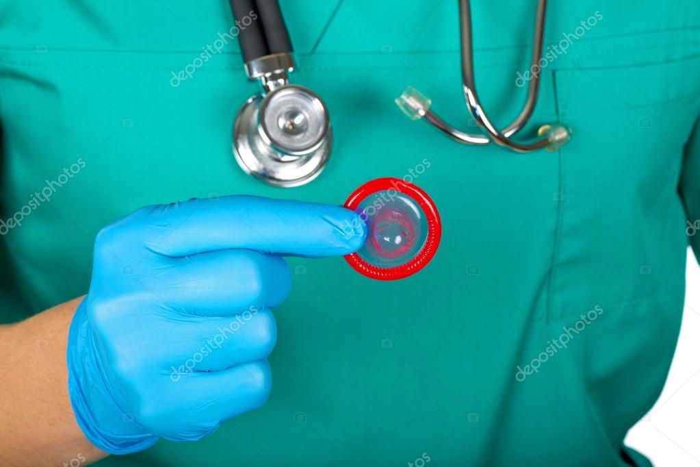 Рука доктора держит красный открытый презерватив 