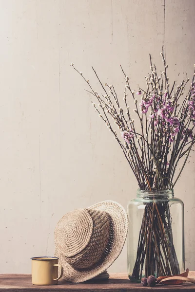 Dry flowers in a vase and vintage hat — Stock Photo, Image