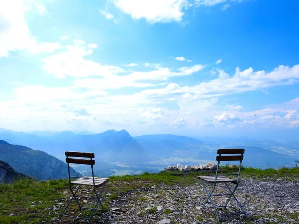 Empty chairs on a mountain top overlooking the valley blue sky clouds hills