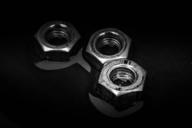 Close up of set of rusty screw-nuts on a black background with copy space