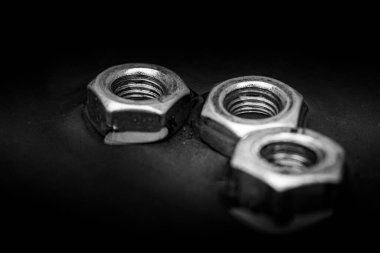 Close up of set of rusty screw-nuts on a black background with copy space