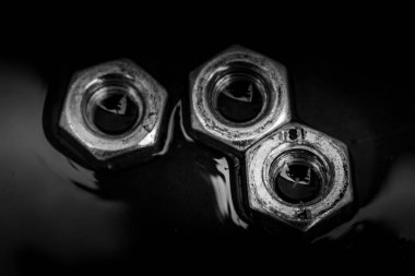 Close up of set of rusty screw-nuts on a black background with copy space