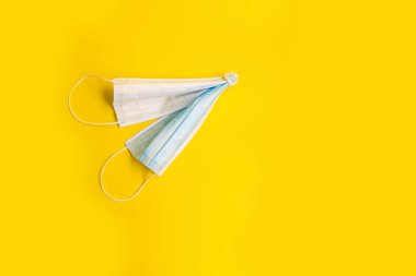 Karantina Tamamlama Konsepti. Beyaz ve mavi tıbbi maskeler uçak şeklinde katlanır, tatildeki bir uçak gibi uçarlar. parlak sarı bir arkaplanda. 