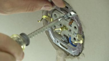 Prizin yanında tornavida tutan teknisyenlere yaklaş. Elektrikçi prizleri elektrik kablolarına bağlar. Kabloyu fişe takın. Adamın biri duvara elektrik prizi takıyor..