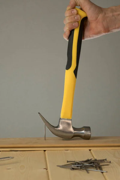 Pull out the nail with a claw hammer. The hammer is removing the nail from the wooden board. Hammer nail puller pull big nail out of the board. Small carpentry work in the workshop. Home renovation