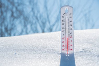Termometre karın üzerinde yatar ve mavi gökyüzünde soğuk havada negatif bir sıcaklık gösterir. Düşük hava ve ortam sıcaklıklarına sahip meteorolojik koşullar. İklim değişikliği ve küresel ısınma