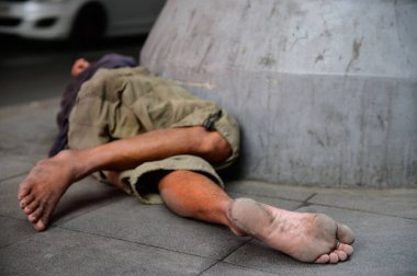 Evsiz bir adam kaldırımda uyuyor.