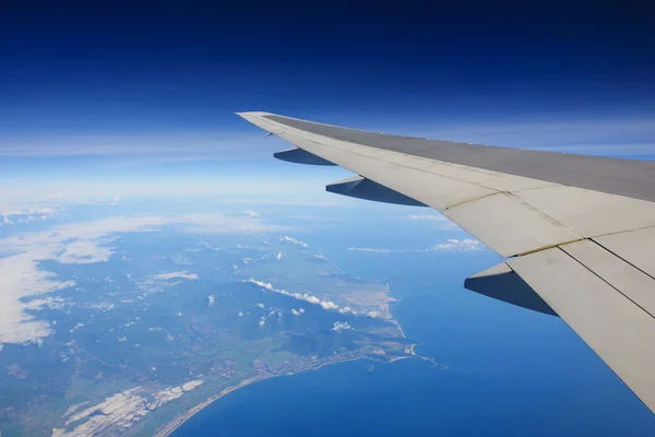 Airplane flying over ocean and island — Stock Photo, Image