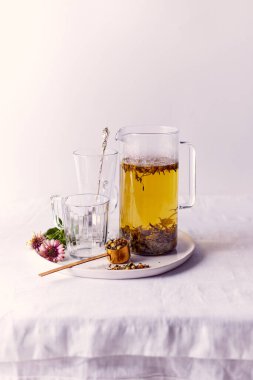 Bardakta bitki çayı ve masada sürahi.