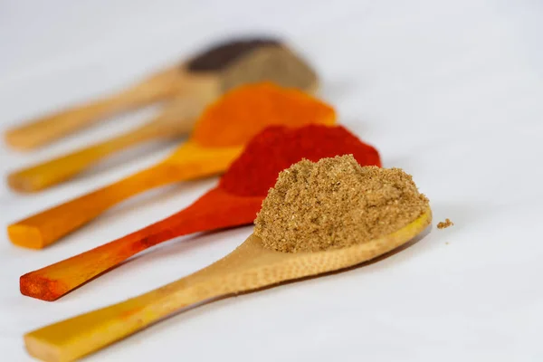 Kerala Style Curry Ingredients In Wooden Spoon. Chilli Powder, Coriander Powder, Turmeric Powder In White Background. Selective Focus On Coriander Powder