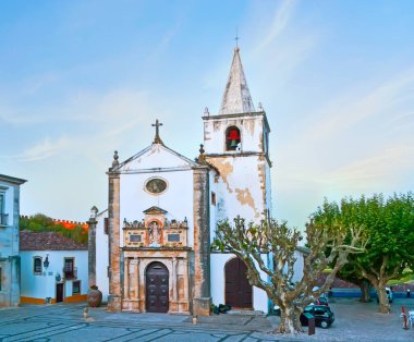 Orta Çağ Santa Maria Kilisesi 'nin ön cephesinde oyulmuş heykeller, duvar sütunları ve küçük çan kulesi, Obidos, Portekiz