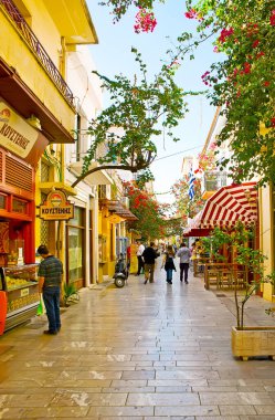 NAFPLIO, GREECE - 11 Ekim 2013: 11 Ekim 'de Nafplio' da, turist kafeleri, hediyelik eşya dükkanları, yemyeşil bougainvillea çalıları ile gölgeli yayalar Vasileos Konstantinou caddesi