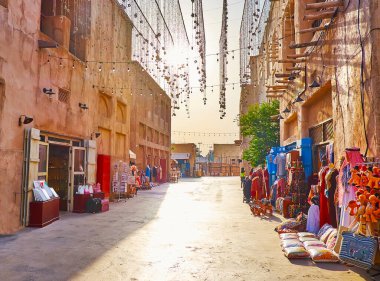 Eski şehirde öğlen yürüyüşü turist tezgahları, sokağın üstündeki çelenkler ve eski kil evler, Al Fahidi, Dubai, BAE