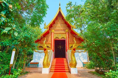 Wat Phra Kaew Tapınağı 'nın göz kamaştırıcı cephesi yaldızlı Naga yılanları - muhafızlar, gable çatı, duvar sütunları ve yontulmuş yaldızlı desenler, Chiang Rai, Tayland