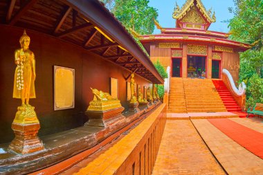Wat Phra Kaew Tapınağı, Chiang Rai, Tayland 'daki Ubosot' un önündeki yaldızlı Buda resimleriyle sokağı keşfedin.