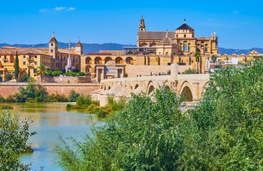 Guadalquivir Nehri kıyısındaki yemyeşil alan Roma Köprüsü, Puerta del Puente kapısı, Mezquita ve Episcopal Sarayı manzaralı karşı kıyıda, Cordoba, İspanya