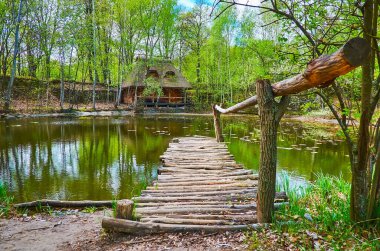 Mamajeva Sloboda Kazak Köyü, Kyiv, Ukrayna 'da küçük bir ahşap balıkçı iskelesi, yemyeşil bir yeşillik ve eski ahşap hata evi olan göl.