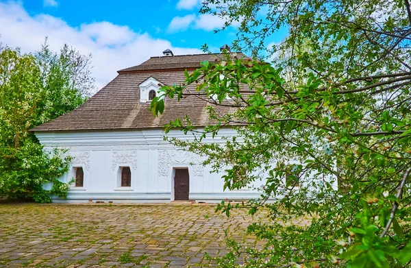 stock image The Ukrainian Baroque style mansion of Sotnyk (military officer of Coassack army) with branches of blooming tree in the foreground, Sotnyk's Estate, Mamajeva Sloboda Cossack Village, Kyiv, Ukraine