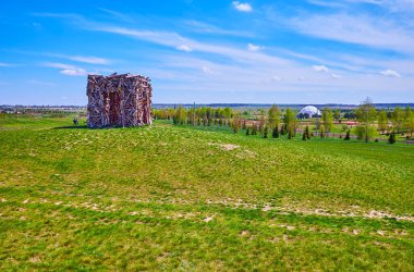 KYIV, UKRAINE - MAY 5, 2021: The green hil, topped with modern installation of wood, representing a cube with passes from each side, on May 5 in Kyiv
