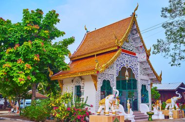 Wat Sangkharam Tapınağı, Lamphun, Tayland gibi iki fil heykelinin koruduğu dantele benzer desenlerle süslenmiş manzaralı beyaz tapınak.