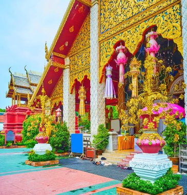 Viharn Luang, girişi önündeki vazolarda altın kaplama desenler, kalıplar, oyulmuş ahşap, heykeller ve altın nilüferler ile süslenmiştir: Wat Phra Bu Hariphunchai Tapınağı, Lamphun, Tayland