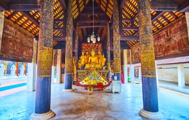 LAMPANG, THAILAND - 8 Mayıs 2019: Lampang 'ın süslü meşe sütunları ve yaldızlı Buda resimleriyle 8 Mayıs' ta Lampang Phra 'lı Ortaçağ ahşap Viharn Nam Taem' i