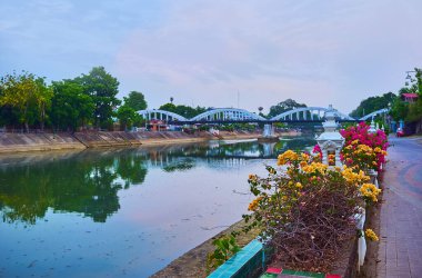 Wang nehri manzaralı keyifli bir akşam nehri yürüyüşü, parlak bougainvillea çiçekleri ve renkli fenerleri olan tarihi Rattanakosin köprüsü, Lampang, Tayland